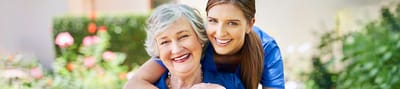 Smiling resident and caregiver in a garden
