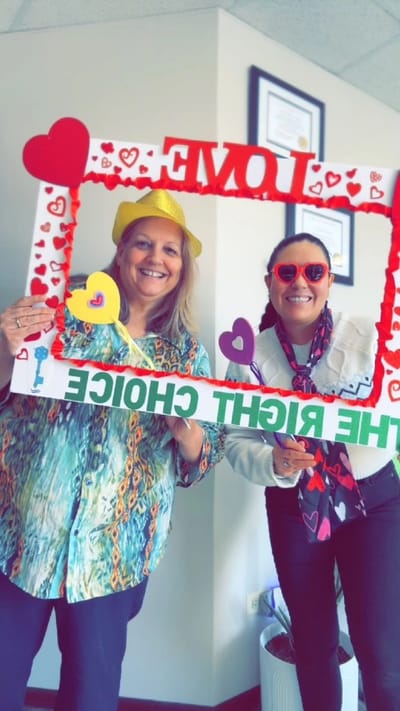 Staff members celebrating with a fun love-themed frame.