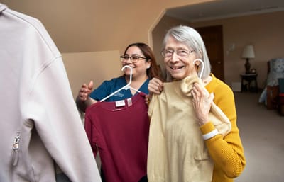 Staff and resident engaging while sorting clothes.