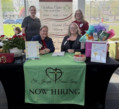 Staff members at a recruitment event with a table setup.