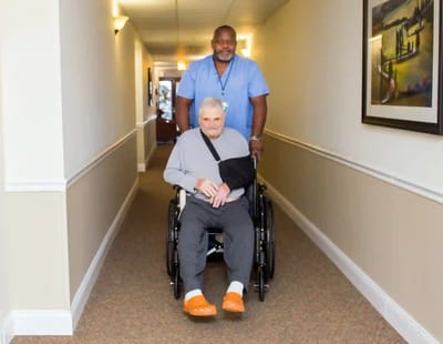 A caregiver assisting a resident in a hallway.