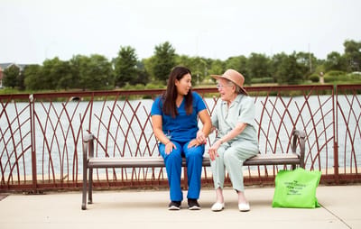 Staff member and senior resident sharing a moment outdoors.
