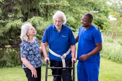 Staff assisting resident with walker outdoors