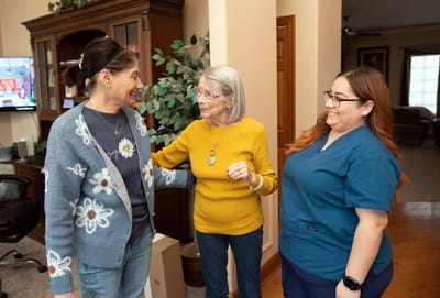 Caregivers interacting with a resident in a cozy living area.