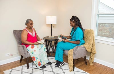 Resident and staff reading together in a cozy setting.