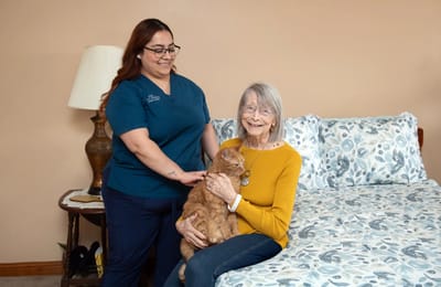 Caregiver with resident holding a cat in bedroom