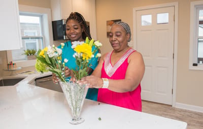 Two women arranging flowers in a kitchen.
