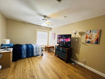 Bright resident room with wooden flooring and furniture.