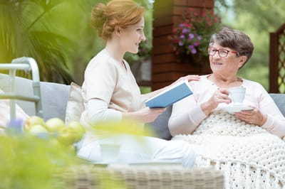 Caregiver talking with a resident outdoors with tea