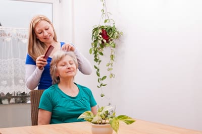 Caregiver styling hair for a resident in a bright room