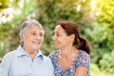 Resident and caregiver sharing a joyful moment outdoors