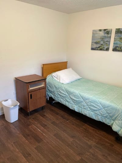 A simple private resident room with a bed and nightstand