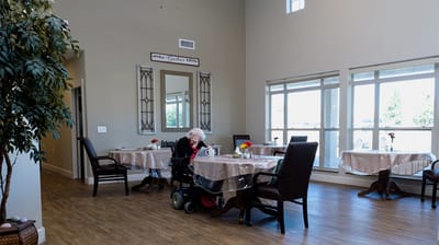 Residents enjoying a common area with tables and plants