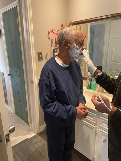 Caregiver assisting resident with shaving in a bathroom