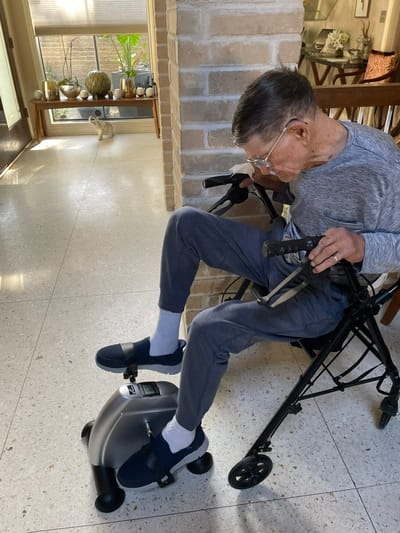 Senior using a foot pedal exerciser in a bright room
