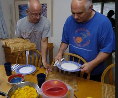 Two residents preparing for a meal at a dining table