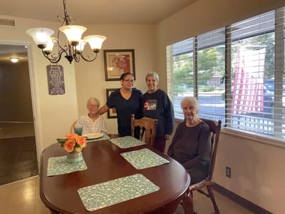 Residents and staff at a dining table in the facility.
