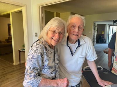 Two residents smiling in the facility lobby.