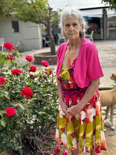 Senior resident enjoying a garden with roses.