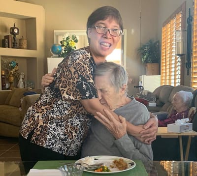 Staff member embraces resident over a meal.