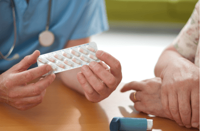 Nurse showing medication to a senior resident.