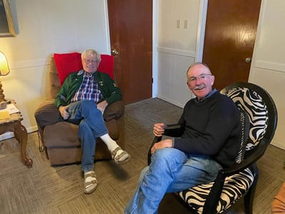 Two smiling residents sitting in a cozy room.