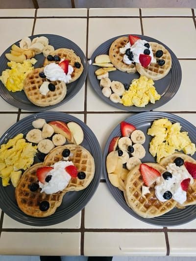 Plated waffles with fruit and scrambled eggs.