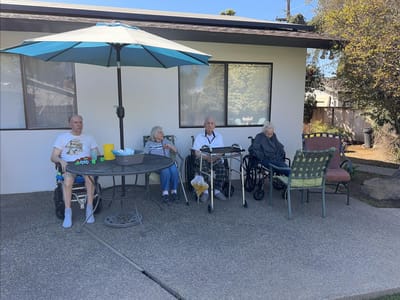 Residents relaxing under an umbrella in an outdoor space.