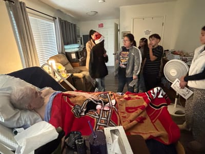 Group of visitors interacting with a resident in bed.