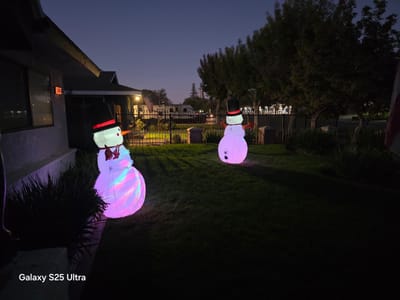 Two glowing snowman decorations in a yard