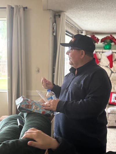Senior man holding a gift inside a room