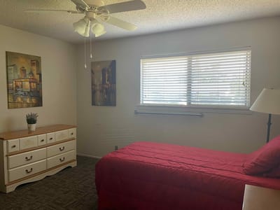 Cozy bedroom with a red bedspread and wall art.