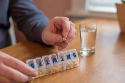 Person organizing medication in a pill organizer.