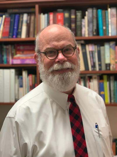 Smiling man in front of bookshelf