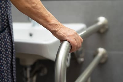 Close-up of an elderly person's hand on a grab bar