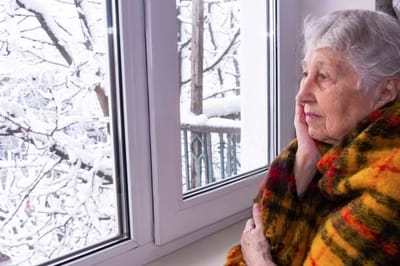 Elderly woman gazing out the snowy window