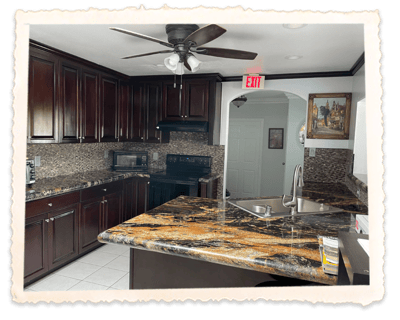 Modern kitchen with dark cabinetry and granite countertops.