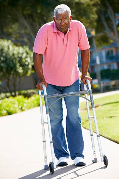An elderly man using a walker in a garden area