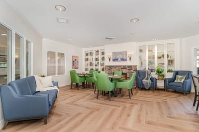 Bright common area with green chairs and natural light