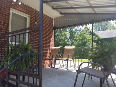 Outdoor seating area with rocking chairs and greenery