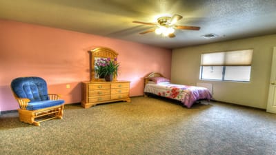 Cozy interior of a resident's room with a single bed and chair