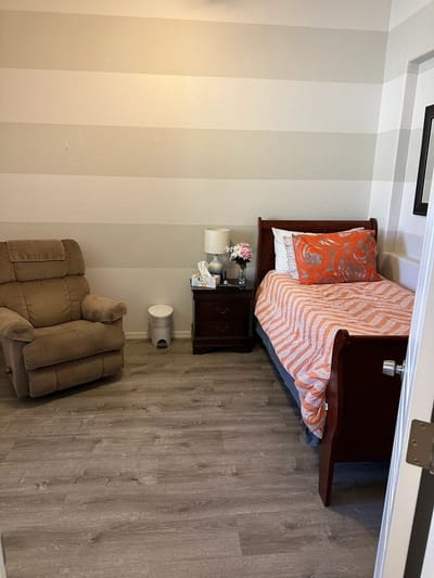 A cozy resident room with a bed and chair