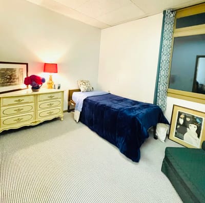 A cozy resident room with a bed and dresser