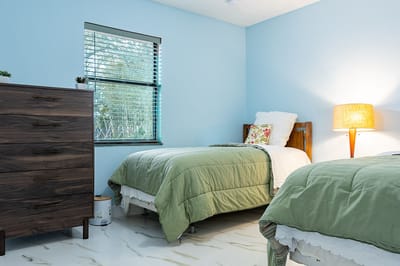 Cozy shared bedroom with green bedding and natural light