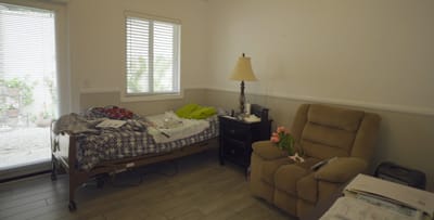 Interior view of a resident's room with a bed and chair