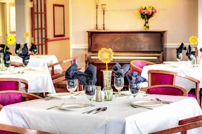 Elegant dining room setup with flowers and piano