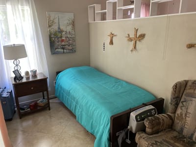 A private resident room with a bed and chair
