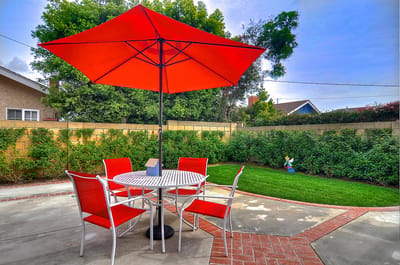 Outdoor patio area with red umbrella and chairs