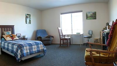 Interior view of a resident's room with a bed and seating area