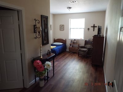 A cozy resident room with a bed and chair